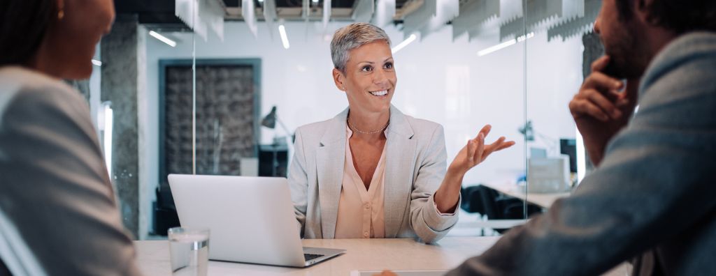 In a conference room, a real estate agent talks to her clients about the homes for sale she has found on the Multiple Listing Service (MLS).