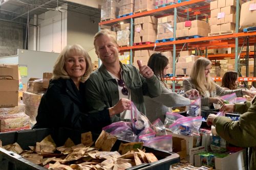 A group of agents and staff from Windermere Utah volunteering in a warehouse. They are putting together donation kits for a local organization Granite Education.