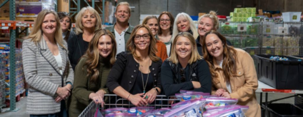 A group of agents and staff from Windermere Utah volunteering in a warehouse. They are putting together donation kits for local organization Granite Education.