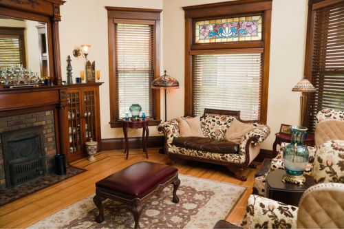The interior of a Victorian architecture home with brown and tan antique furniture and accessories, traditional furnishings, and stained-glass windows.