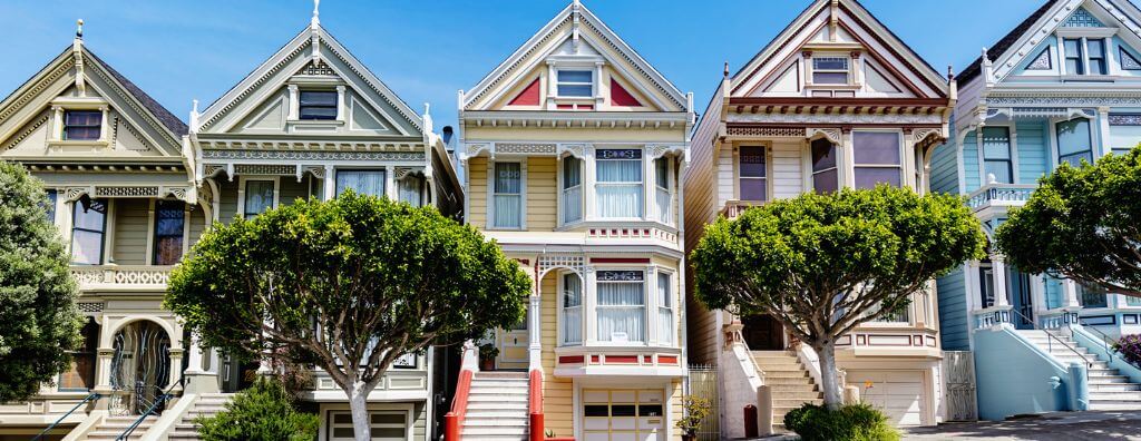 A street-level view of the Painted Ladies Victorian architecture homes at Alamo Square in San Francisco, California.