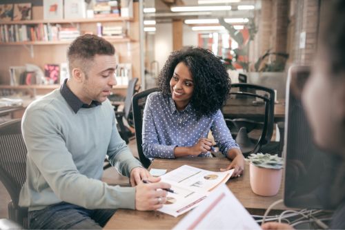 A Black woman real estate agent is showing research on home prices to her client who is looking to sell their home.