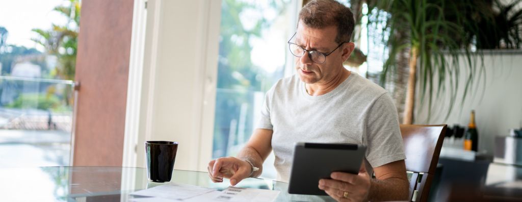 A middle-aged white man is researching home prices at his dinner table as he prepares to sell his house.