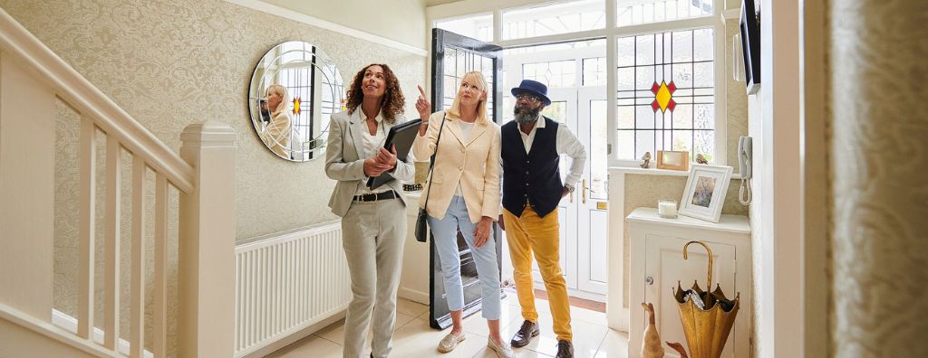 A black woman real estate agent shows a house to a senior interracial (black and white) husband and wife. They discuss the seller’s pre-listing inspection.