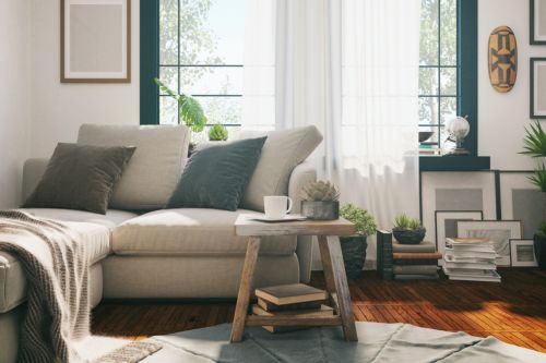 An airy and minimalist living room with a small coffee table and hardwood floors with neutral color palette of cream, taupe, and blue shows how to design a small corner that looks lived in and stylish. 