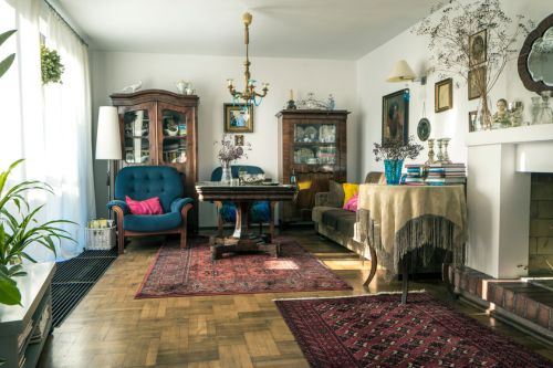 An example of traditional interior design: a classic living room with dark wood features, traditional furnishings, wood cabinets with glass windows, and a patterned carpet over hardwood flooring.