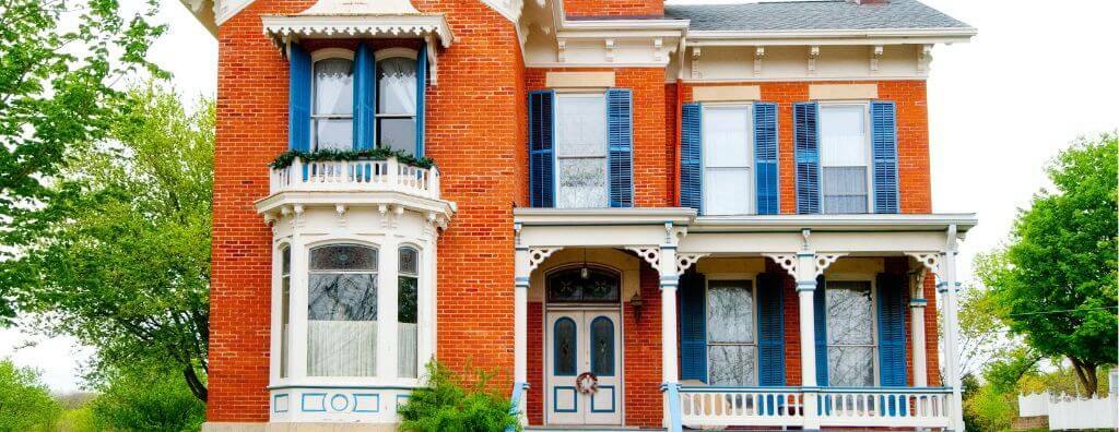 An example of Italianate architecture: a brick three-story house with decorative windows and a columned entryway. Ornate details are found throughout the woodwork.