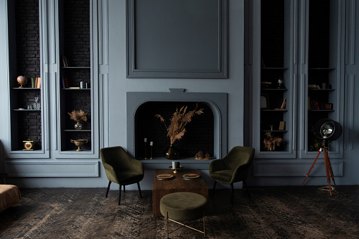Classic room interior featuring green armchairs, wooden table, and decorative fireplace